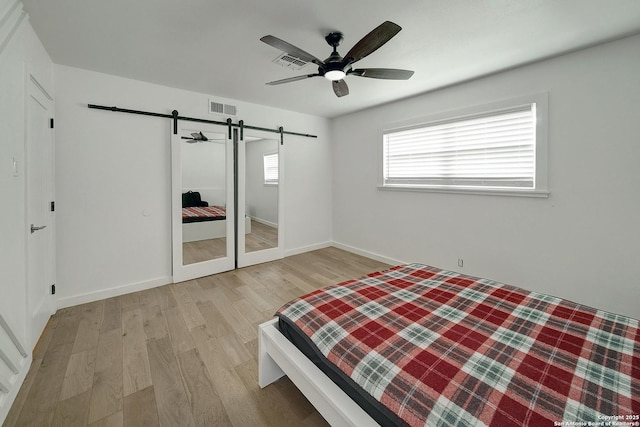 5738 Brenda Ln, San Antonio, TX 78240 - bedroom with a barn door, light wood-style flooring, and ceiling fan
