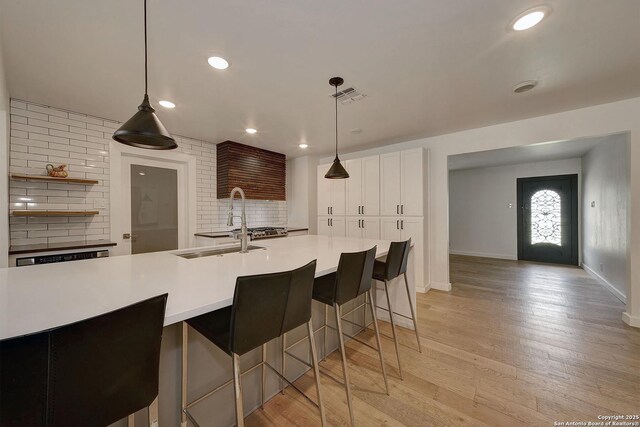 5738 Brenda Ln, San Antonio, TX 78240 - kitchen featuring light countertops, white cabinets, a breakfast bar, backsplash, and light wood-style floors