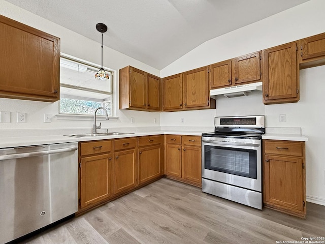 1222 Bobcat Pass, San Antonio, TX 78251 - kitchen featuring appliances with stainless steel finishes, under cabinet range hood, brown cabinets, lofted ceiling, and light wood-style floors