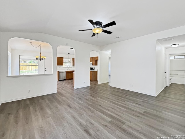 1222 Bobcat Pass, San Antonio, TX 78251 - unfurnished living room featuring arched walkways, a chandelier, wood finished floors, ceiling fan, and vaulted ceiling