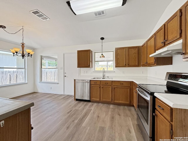 1222 Bobcat Pass, San Antonio, TX 78251 - kitchen featuring stainless steel appliances, under cabinet range hood, brown cabinetry, light wood-style flooring, and decorative light fixtures
