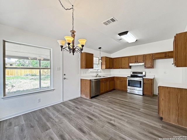 1222 Bobcat Pass, San Antonio, TX 78251 - kitchen featuring stainless steel appliances, under cabinet range hood, lofted ceiling, brown cabinets, and a chandelier