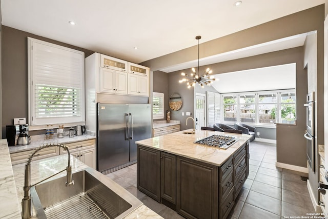 133 E Mistletoe Ave, San Antonio, TX 78212 - kitchen featuring stainless steel appliances, open floor plan, light stone countertops, a chandelier, and dark brown cabinetry