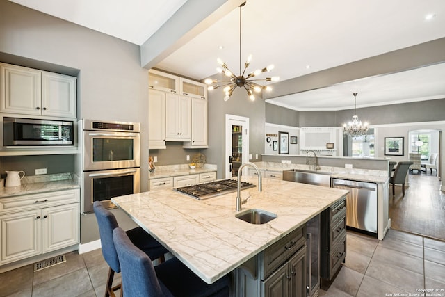 133 E Mistletoe Ave, San Antonio, TX 78212 - kitchen with a chandelier, appliances with stainless steel finishes, light stone countertops, light tile patterned flooring, and an island with sink