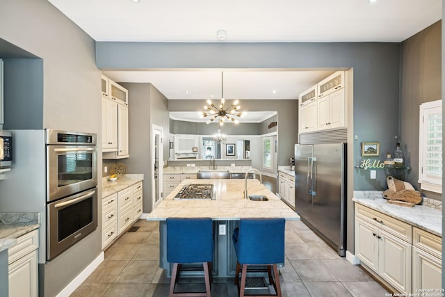 133 E Mistletoe Ave, San Antonio, TX 78212 - kitchen featuring stainless steel appliances, a chandelier, an island with sink, a breakfast bar area, and glass insert cabinets