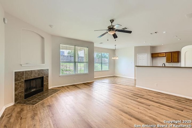 2727 Encino Riv, San Antonio, TX 78259 - unfurnished living room featuring a tile fireplace, light wood finished floors, ceiling fan, recessed lighting, and a chandelier