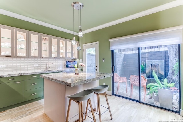 117 Saint Dennis Unit 117, San Antonio, TX 78209 - kitchen with green cabinets, crown molding, light wood-style flooring, a breakfast bar, and a kitchen island