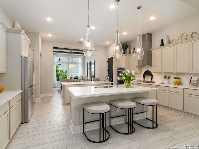 25022 Dulzura, San Antonio, TX 78261 - kitchen with wall chimney exhaust hood, stainless steel appliances, a center island with sink, a breakfast bar area, and light countertops
