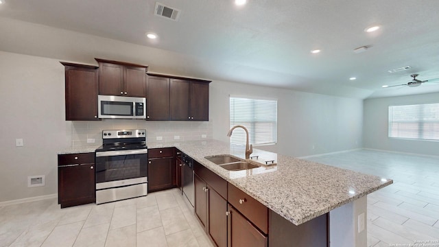 2076 Meadow Pipit, New Braunfels, TX 78130 - kitchen featuring appliances with stainless steel finishes, a peninsula, decorative backsplash, light stone counters, and healthy amount of natural light