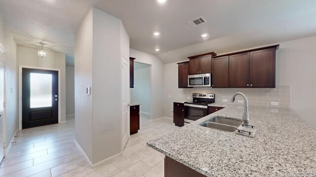 2076 Meadow Pipit, New Braunfels, TX 78130 - kitchen featuring stainless steel appliances, backsplash, light stone countertops, dark brown cabinets, and light tile patterned floors