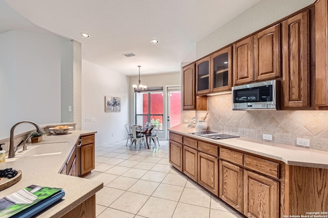 34 Roseheart, San Antonio, TX 78259 - kitchen featuring stainless steel microwave, tasteful backsplash, light tile patterned flooring, a chandelier, and light countertops
