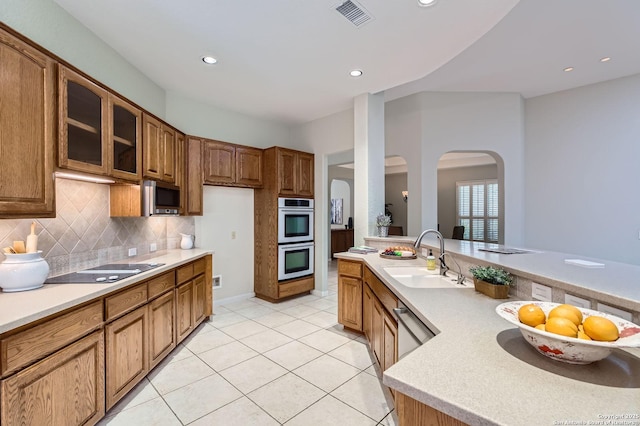 34 Roseheart, San Antonio, TX 78259 - kitchen featuring appliances with stainless steel finishes, arched walkways, light countertops, brown cabinetry, and recessed lighting