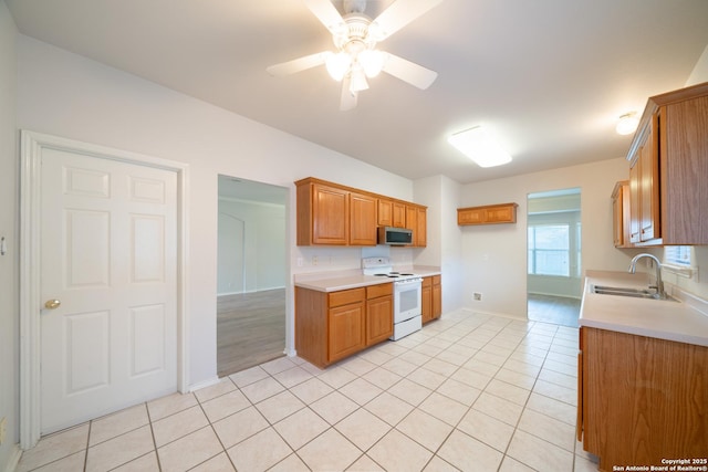 16914 Redhorse Pass, San Antonio, TX 78247 - kitchen featuring white range with electric stovetop, stainless steel microwave, light countertops, light tile patterned floors, and brown cabinets