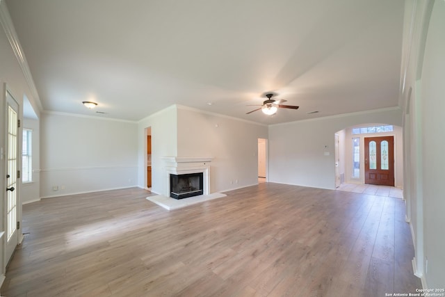 16914 Redhorse Pass, San Antonio, TX 78247 - unfurnished living room with light wood-type flooring, a ceiling fan, a fireplace with raised hearth, ornamental molding, and arched walkways