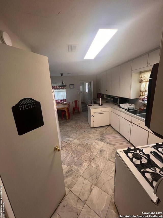 4849 Briarbend, Houston, TX 77035 - kitchen with white range with gas stovetop, light marble finish floors, a peninsula, stainless steel microwave, and white cabinets