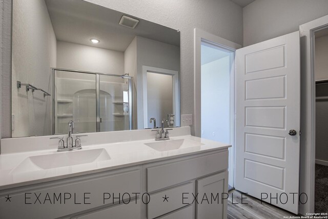 4311 Clarisse St, New Braunfels, TX 78130 - bathroom featuring a stall shower, double vanity, and wood finished floors