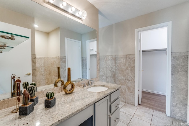 3316 Fresno, Schertz, TX 78154 - bathroom featuring tile walls, tile patterned floors, vanity, a spacious closet, and a wainscoted wall