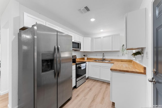 338 Tomrob Dr, San Antonio, TX 78220 - kitchen with stainless steel appliances, wood counters, light wood-style flooring, white cabinetry, and recessed lighting