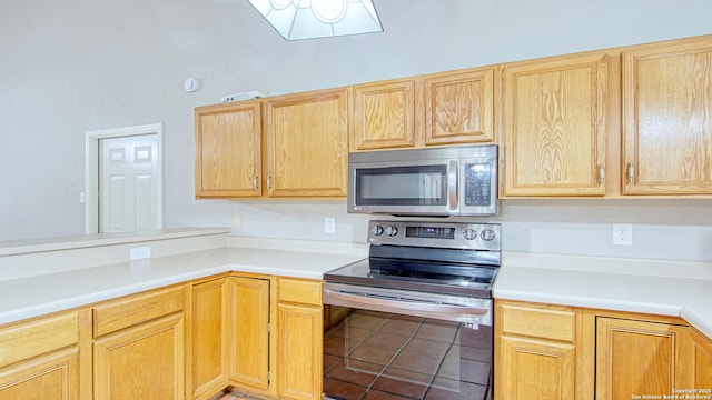 103 Weese, Pleasanton, TX 78064 - kitchen featuring appliances with stainless steel finishes, light countertops, light brown cabinetry, and a peninsula
