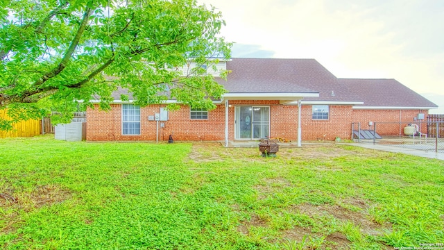 103 Weese, Pleasanton, TX 78064 - back of property featuring an outdoor fire pit, a shingled roof, brick siding, and a patio area