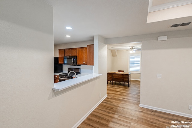 5038 Sandhill Crane, San Antonio, TX 78253 - kitchen featuring black microwave, stainless steel gas range oven, brown cabinets, light wood-type flooring, and light countertops