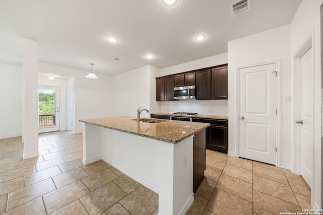 14724 Costa Leon, San Antonio, TX 78245 - kitchen featuring stainless steel appliances, light stone countertops, backsplash, dark brown cabinets, and a center island with sink