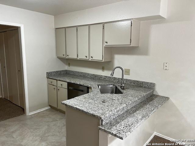 9351 Dover Rdg, San Antonio, TX 78250 - kitchen featuring a peninsula, stainless steel dishwasher, light stone countertops, and a breakfast bar