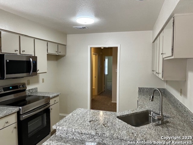 9351 Dover Rdg, San Antonio, TX 78250 - kitchen featuring appliances with stainless steel finishes, a textured ceiling, and light stone counters