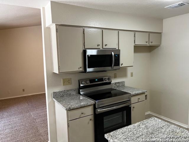 9351 Dover Rdg, San Antonio, TX 78250 - kitchen with stainless steel appliances, carpet floors, and light stone counters