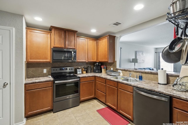 1826 Strawhouse, San Antonio, TX 78245 - kitchen featuring appliances with stainless steel finishes, backsplash, light tile patterned floors, arched walkways, and recessed lighting