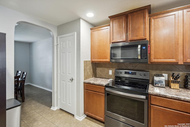 1826 Strawhouse, San Antonio, TX 78245 - kitchen with stainless steel appliances, arched walkways, decorative backsplash, light tile patterned floors, and recessed lighting