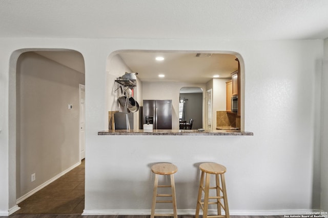 1826 Strawhouse, San Antonio, TX 78245 - kitchen featuring appliances with stainless steel finishes, arched walkways, dark tile patterned flooring, recessed lighting, and a kitchen breakfast bar
