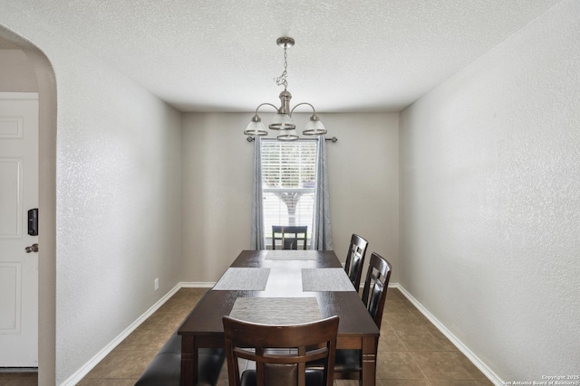 1826 Strawhouse, San Antonio, TX 78245 - dining area featuring arched walkways, dark tile patterned flooring, a chandelier, a textured ceiling, and a textured wall