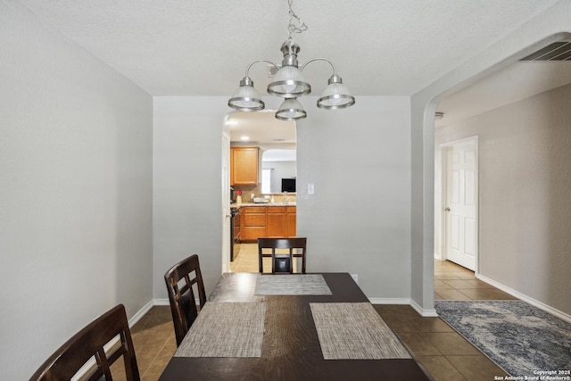 1826 Strawhouse, San Antonio, TX 78245 - dining area with arched walkways, tile patterned flooring, a chandelier, and a textured ceiling