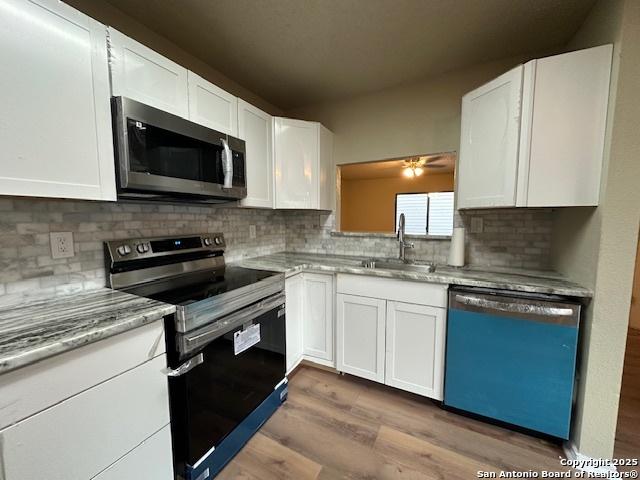 16454 Blanco Ky, San Antonio, TX 78247 - kitchen with appliances with stainless steel finishes, dark wood-style flooring, white cabinetry, and decorative backsplash