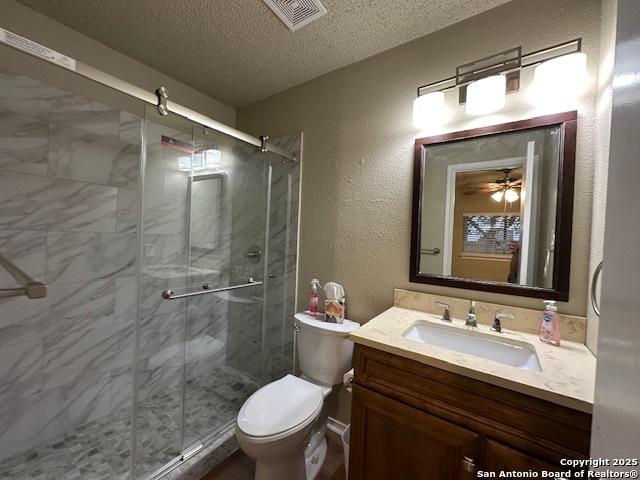 16454 Blanco Ky, San Antonio, TX 78247 - full bath with vanity, a textured ceiling, a textured wall, and a stall shower
