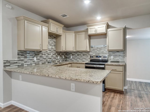 122 Adrian, San Antonio, TX 78213 - kitchen featuring stainless steel electric stove, a peninsula, light wood-type flooring, decorative backsplash, and cream cabinetry