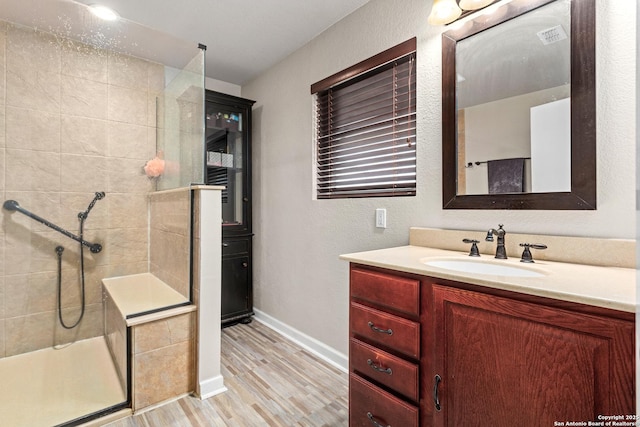 177 Lakeview Cir, La Vernia, TX 78121 - bathroom with tiled shower, vanity, wood finished floors, and a textured wall