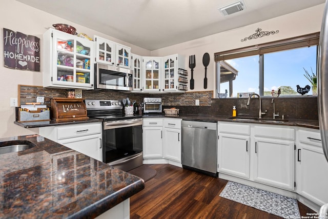 177 Lakeview Cir, La Vernia, TX 78121 - kitchen with appliances with stainless steel finishes, dark wood finished floors, white cabinets, decorative backsplash, and glass insert cabinets