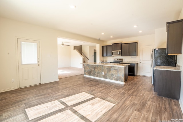 7335 Sharma Vly, San Antonio, TX 78252 - kitchen featuring stainless steel microwave, white range with electric cooktop, wood finished floors, an island with sink, and recessed lighting