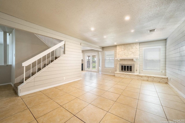 6914 Ludgate, San Antonio, TX 78239 - unfurnished living room with stairs, a textured ceiling, tile patterned floors, wooden walls, and a fireplace
