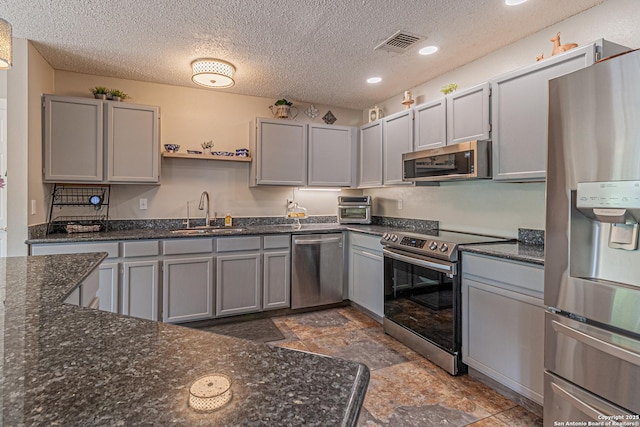 7907 Donshire, Converse, TX 78109 - kitchen featuring appliances with stainless steel finishes, gray cabinetry, a textured ceiling, dark stone counters, and recessed lighting
