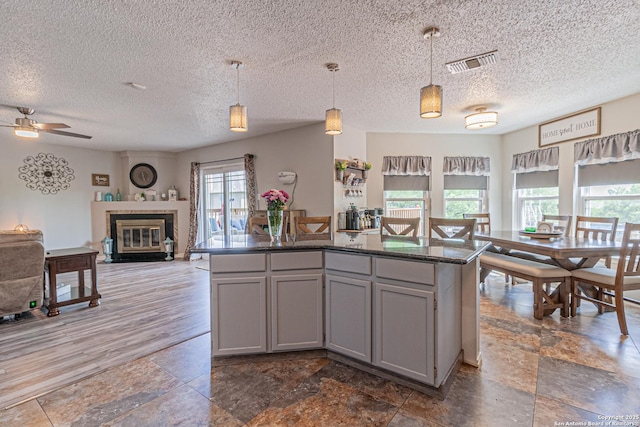 7907 Donshire, Converse, TX 78109 - kitchen with gray cabinetry, a textured ceiling, ceiling fan, decorative light fixtures, and a center island