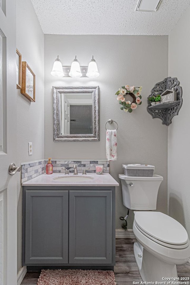 7907 Donshire, Converse, TX 78109 - half bath with wood finished floors, vanity, and a textured ceiling