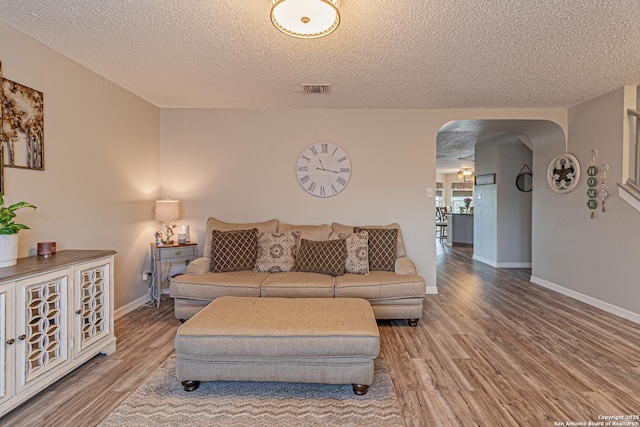 7907 Donshire, Converse, TX 78109 - living room featuring arched walkways, a textured ceiling, and wood finished floors
