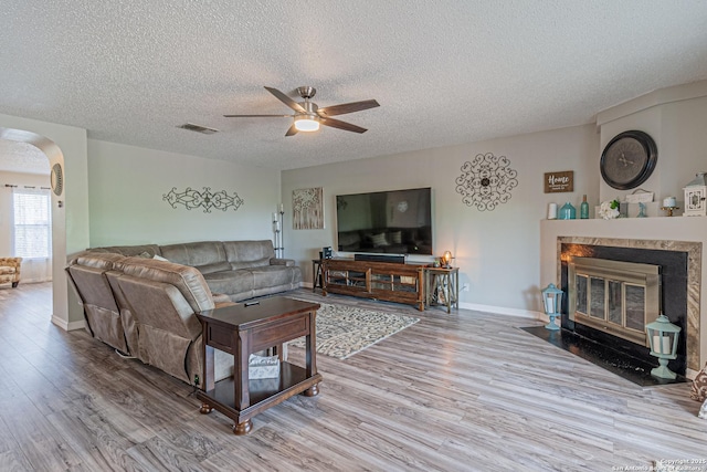 7907 Donshire, Converse, TX 78109 - living area featuring wood finished floors, arched walkways, a textured ceiling, a ceiling fan, and a tiled fireplace