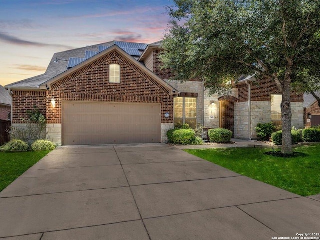 25619 Poerner Trl, San Antonio, TX 78261 - view of front of house featuring a garage, stone siding, driveway, brick siding, and solar panels
