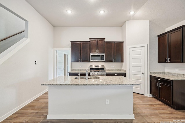 11518 Biddle, San Antonio, TX 78253 - kitchen with appliances with stainless steel finishes, dark brown cabinets, light stone countertops, a kitchen island with sink, and recessed lighting