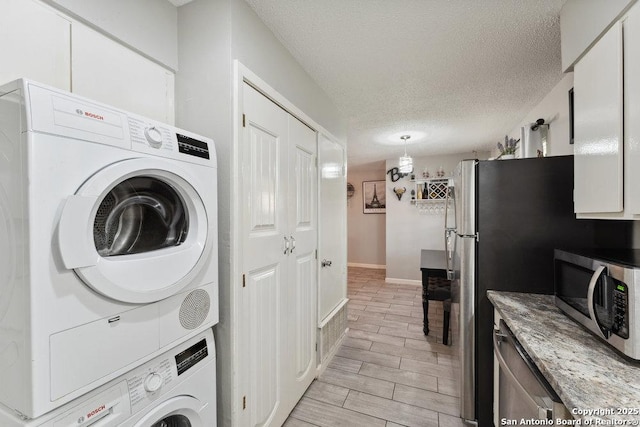 923 Vance Jackson, San Antonio, TX 78201 - laundry room with estacked washer and dryer, a textured ceiling, and wood finish floors