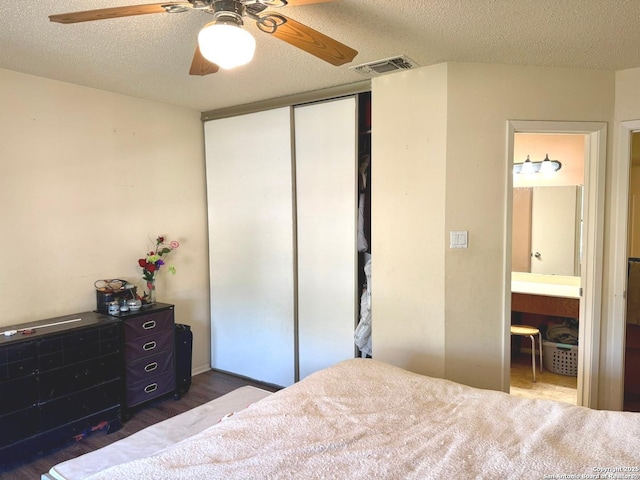 11733 Spring Rdg, San Antonio, TX 78249 - bedroom featuring a closet, a textured ceiling, dark wood-style floors, connected bathroom, and a ceiling fan